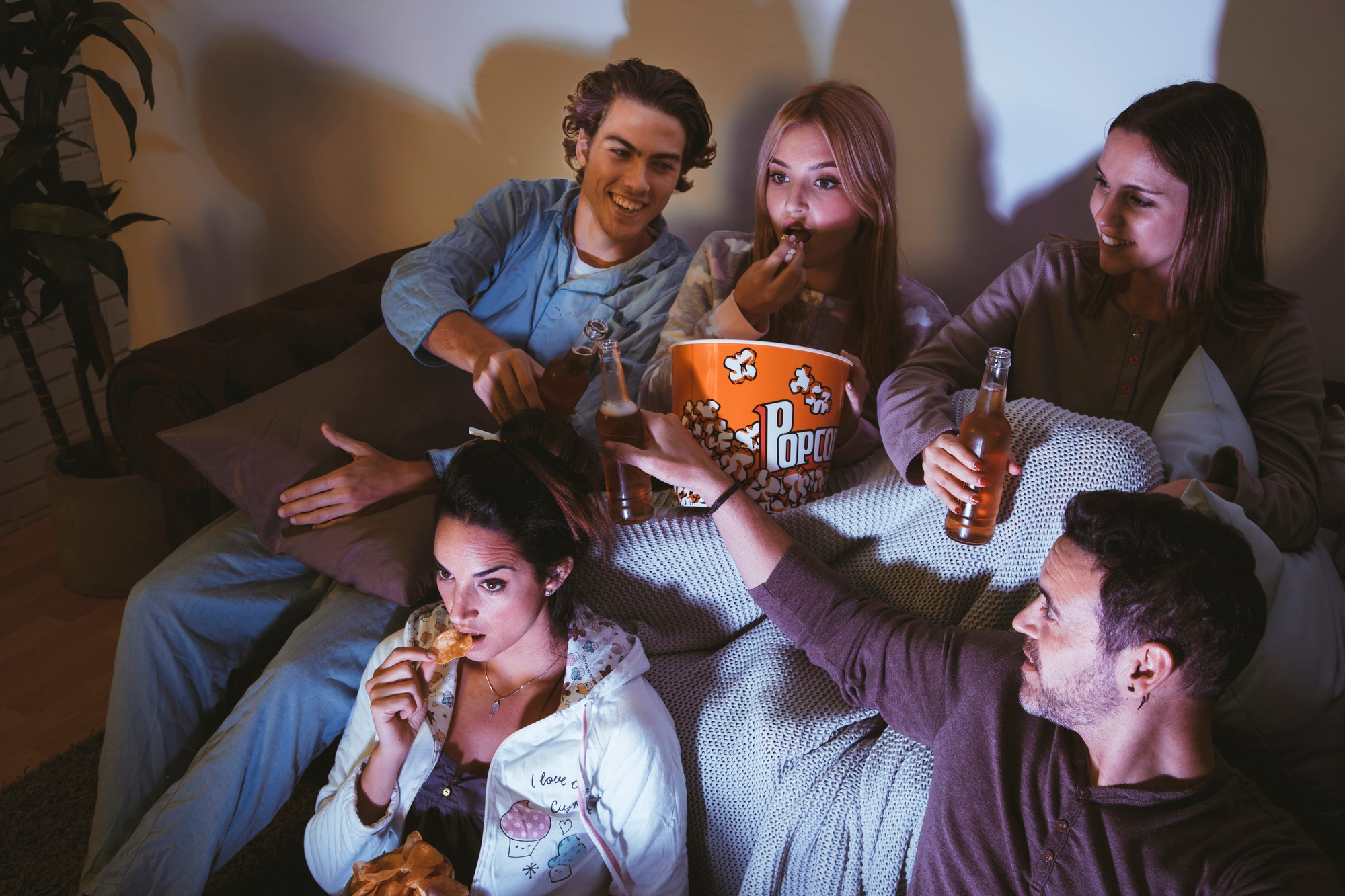 A group of friends enjoying snacks and drinks together during a movie night, sharing a cozy and cheerful atmosphere.
