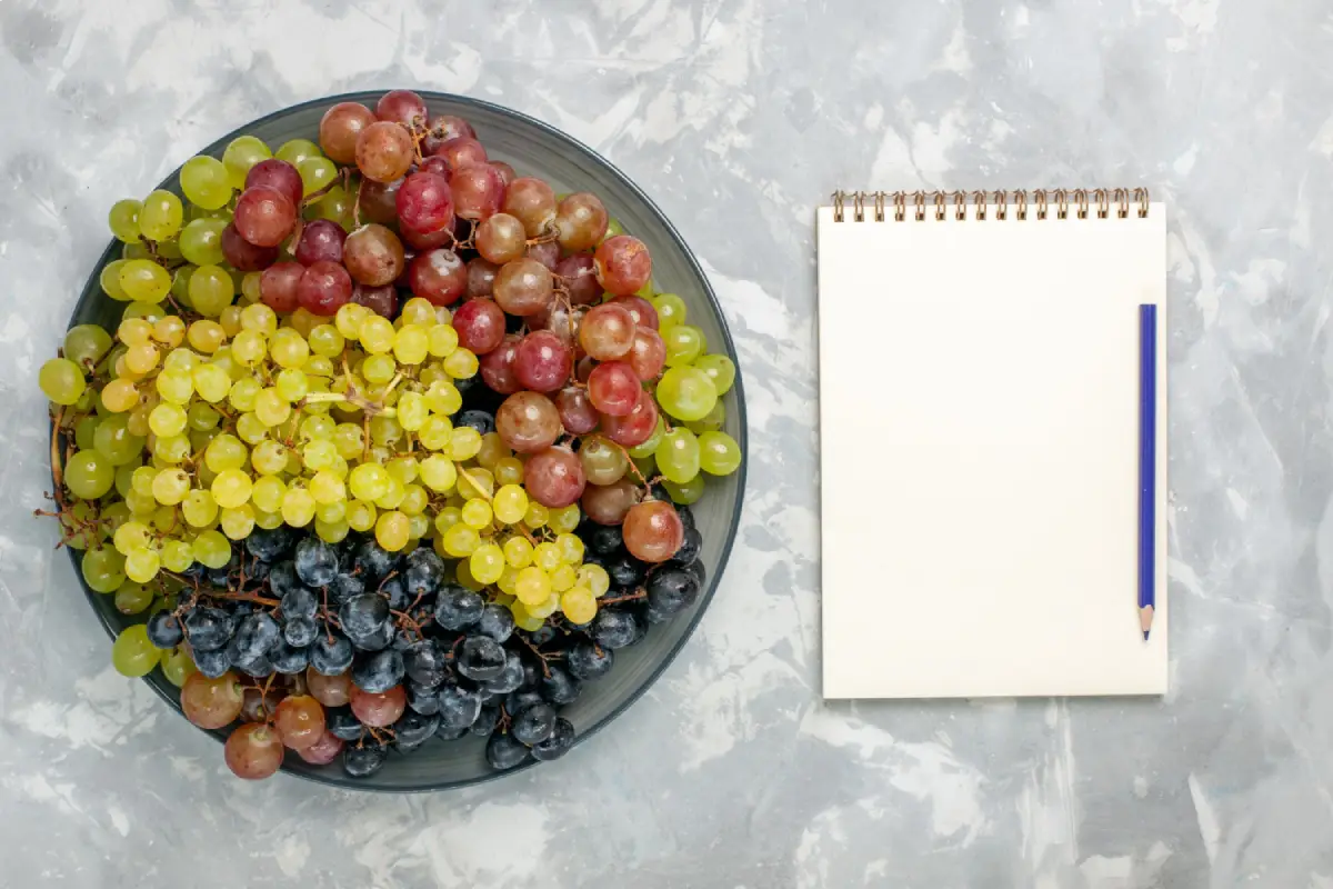 A variety of grapes next to a notebook, ready for jotting down nutritional information