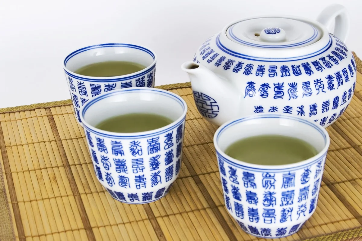 A traditional white and blue Chinese tea set, with a teapot and cups on a bamboo mat.
