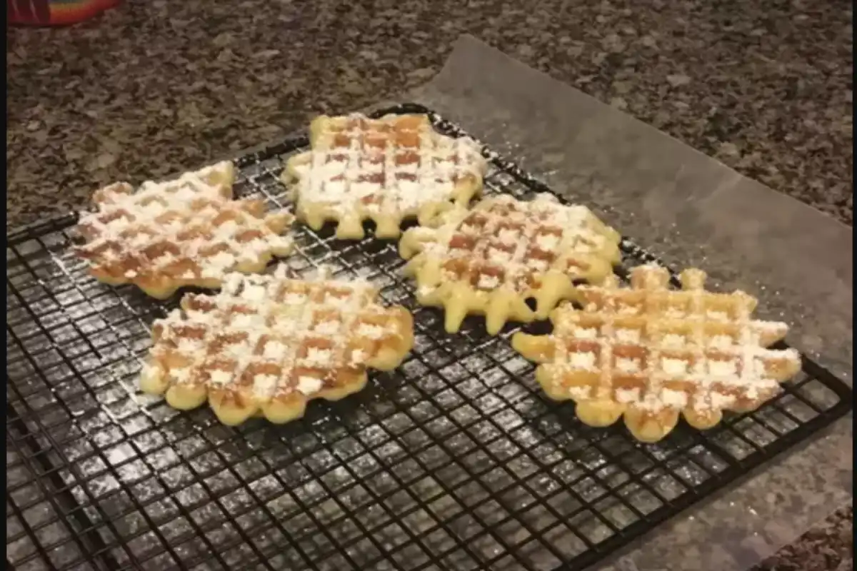 A waffle cookies dusted with powdered sugar on a cooling rack