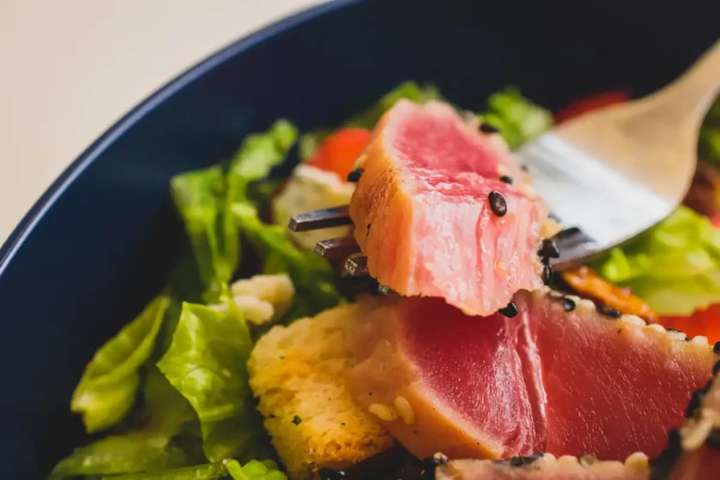 a fresh Ahi Tuna Salad with seared tuna slices, crisp lettuce, and juicy tomatoes, sprinkled with black sesame seeds