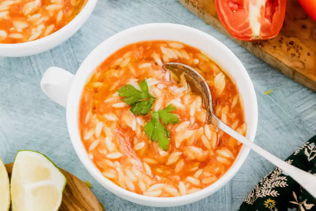 Is Orzo the Same as Pastina? - A bowl of tomato soup with orzo pasta, garnished with parsley.