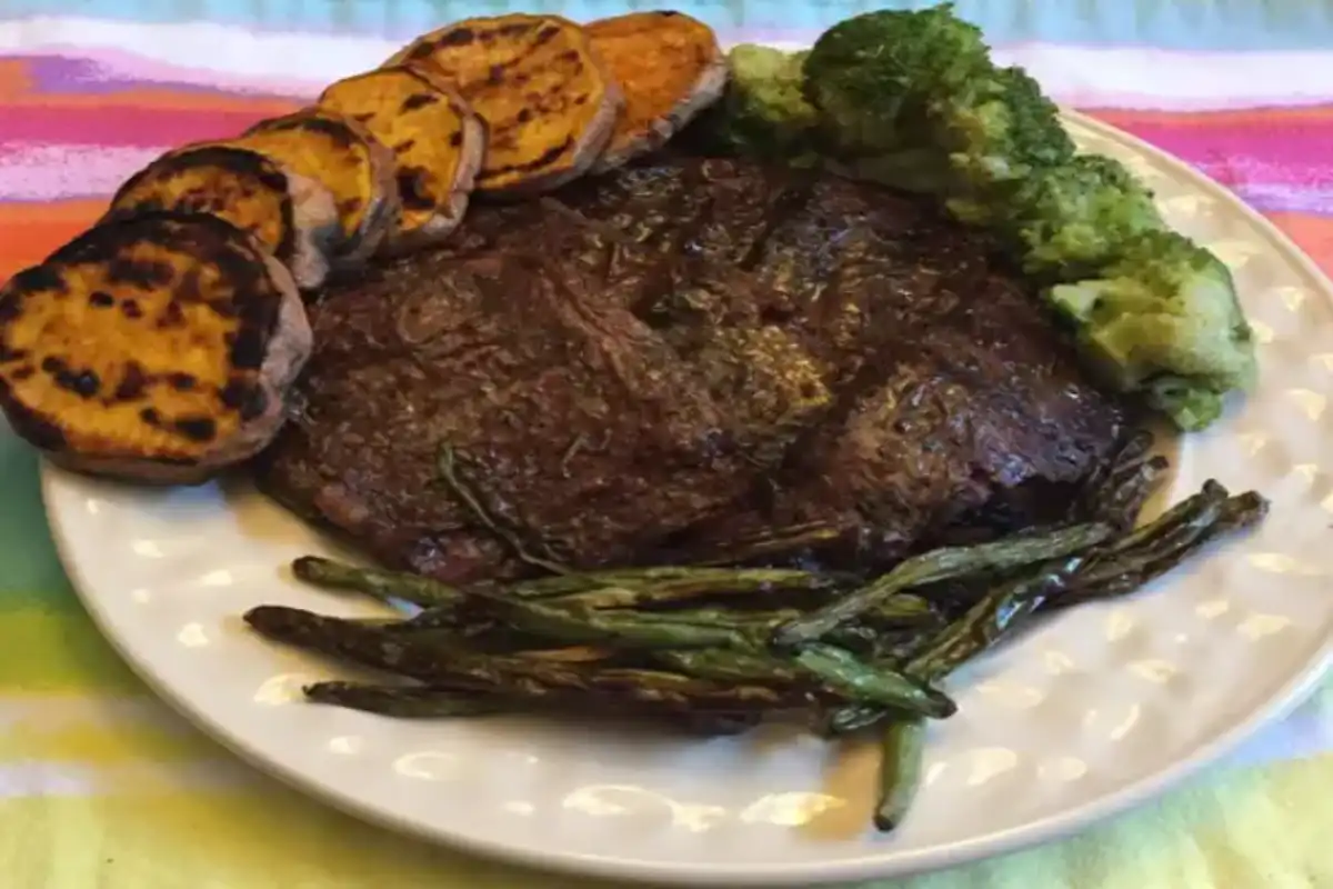 A plate of nutritious skirt steak served with grilled sweet potatoes, roasted asparagus, and steamed broccoli.