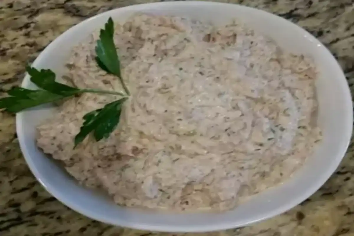 A bowl of Barbie's Tuna Salad, garnished with a sprig of parsley, ready to be served as part of the recipe directions