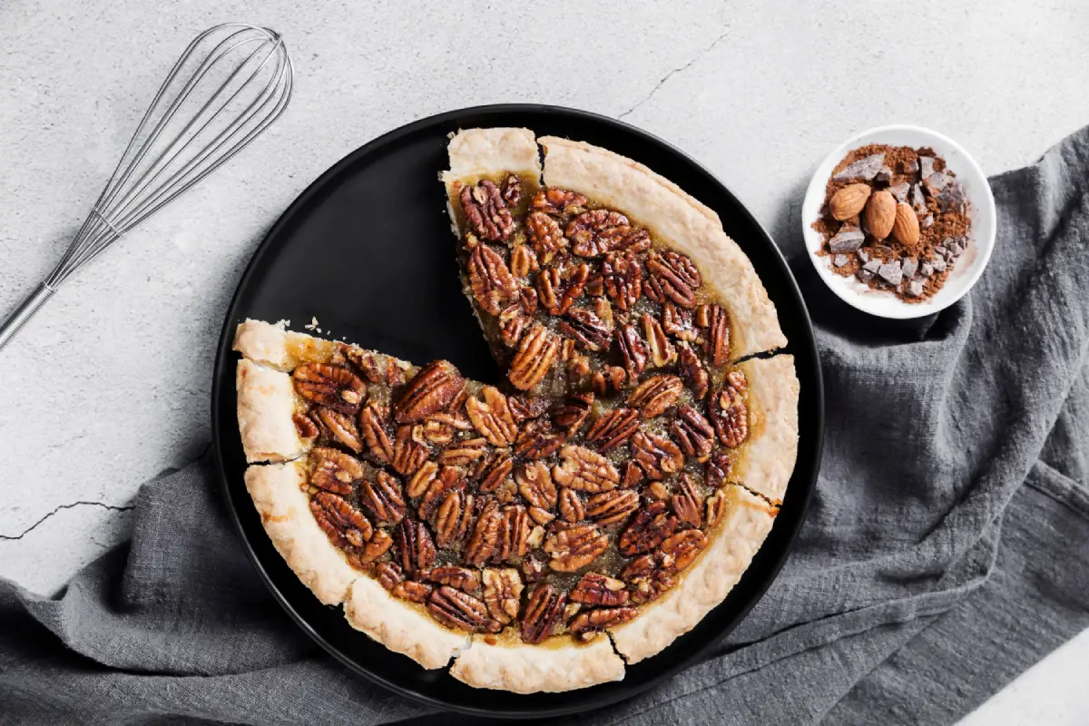 Freshly baked pecan pie on a black plate, showcasing the delicious results of using pecans in baking.