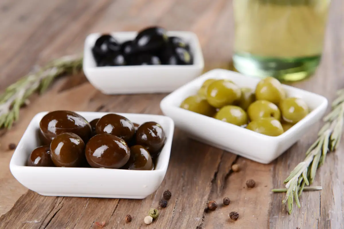 Kalamata and green olives in separate bowls with rosemary and olive oil bottle