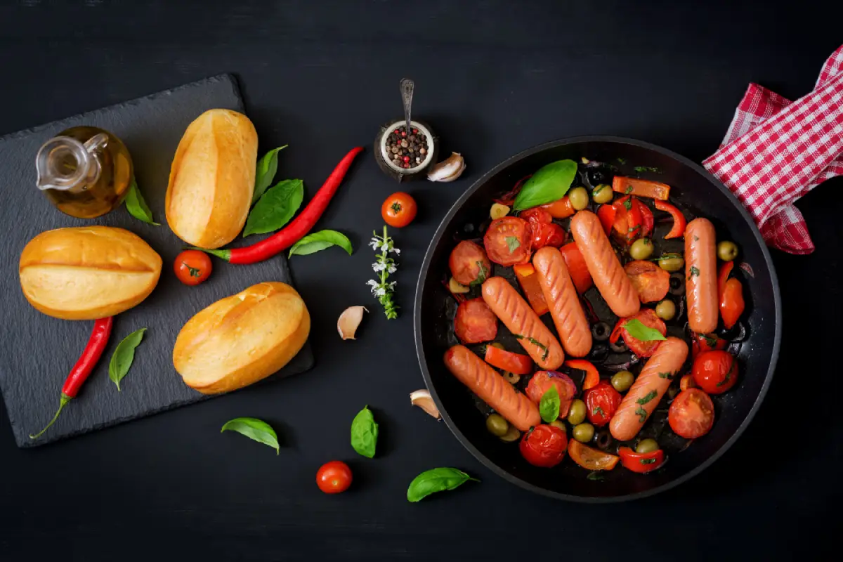Grilled red sausages with vegetables in a Greek-style pan, ready to serve