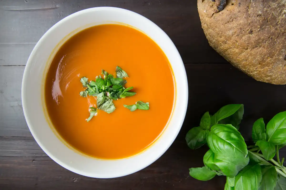 A smooth chicken tomato soup garnished with fresh herbs, symbolizing Italian culinary healing traditions.
