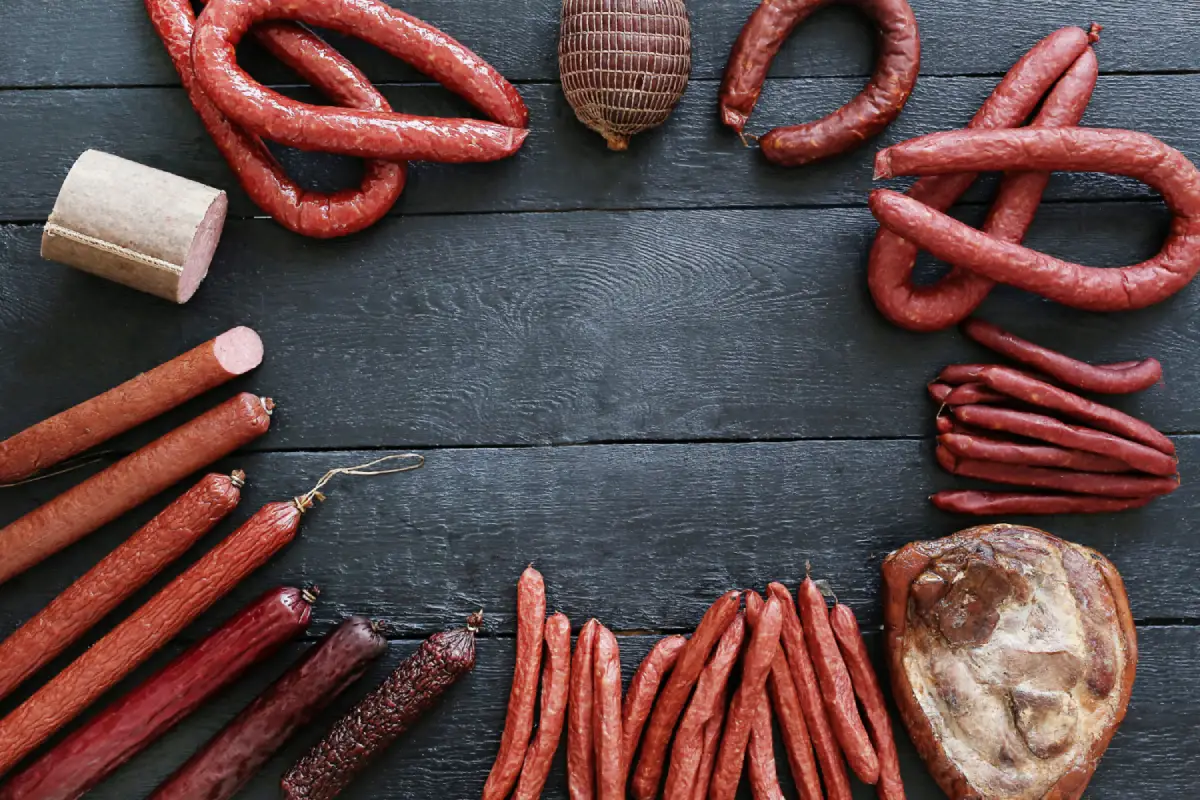 Assorted types of sausages displayed on a dark wooden surface