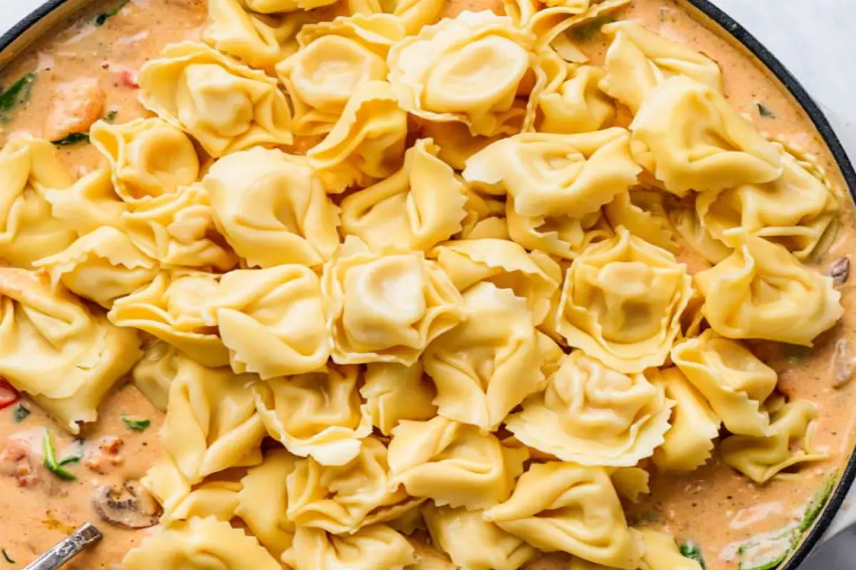 Fresh tortellini in a rich, creamy sauce, ready for cooking.