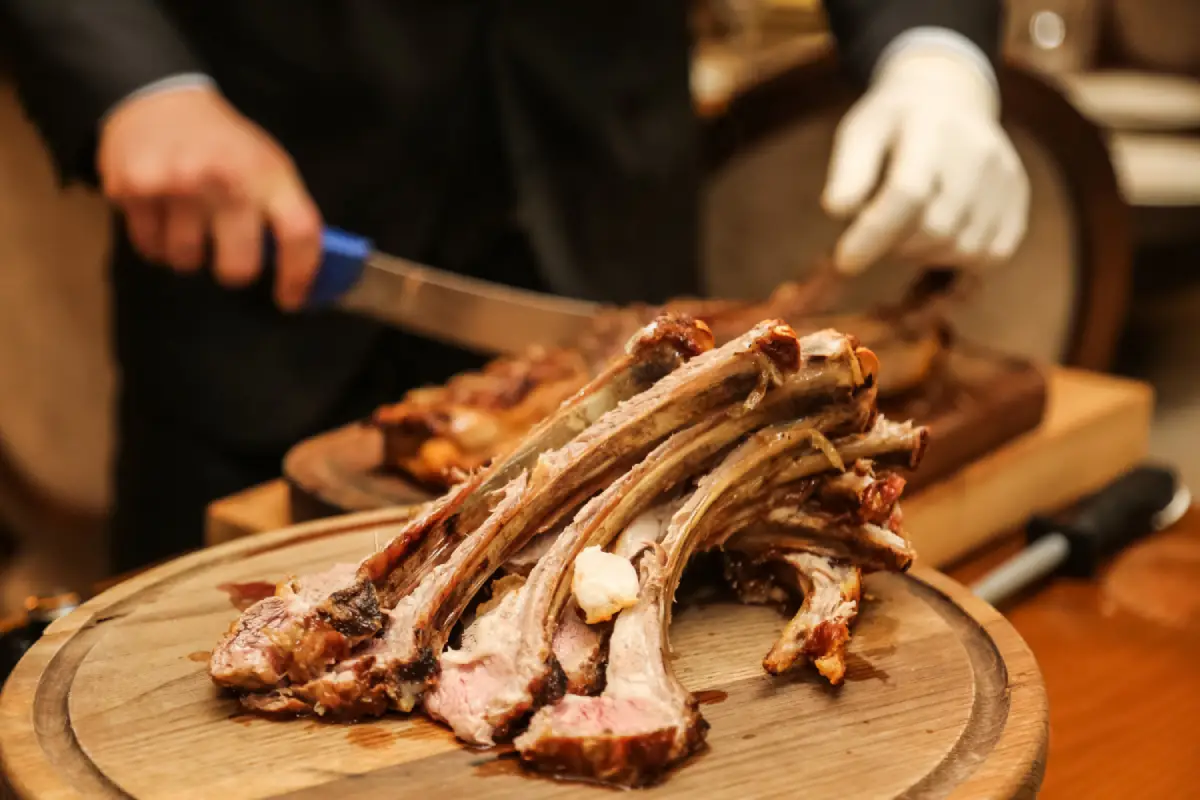  A chef expertly carving succulent beef ribs on a wooden cutting board.