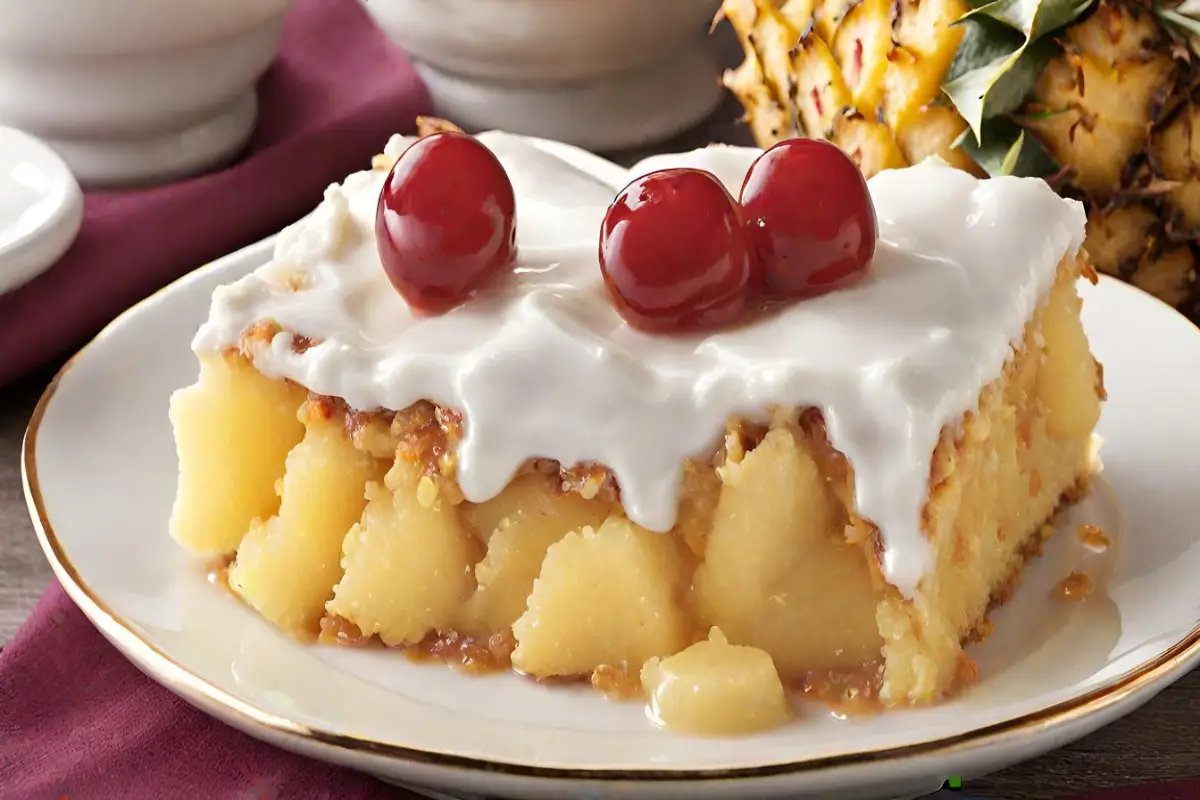 A luscious slice of Pineapple Dump Cake topped with creamy frosting and cherries.
