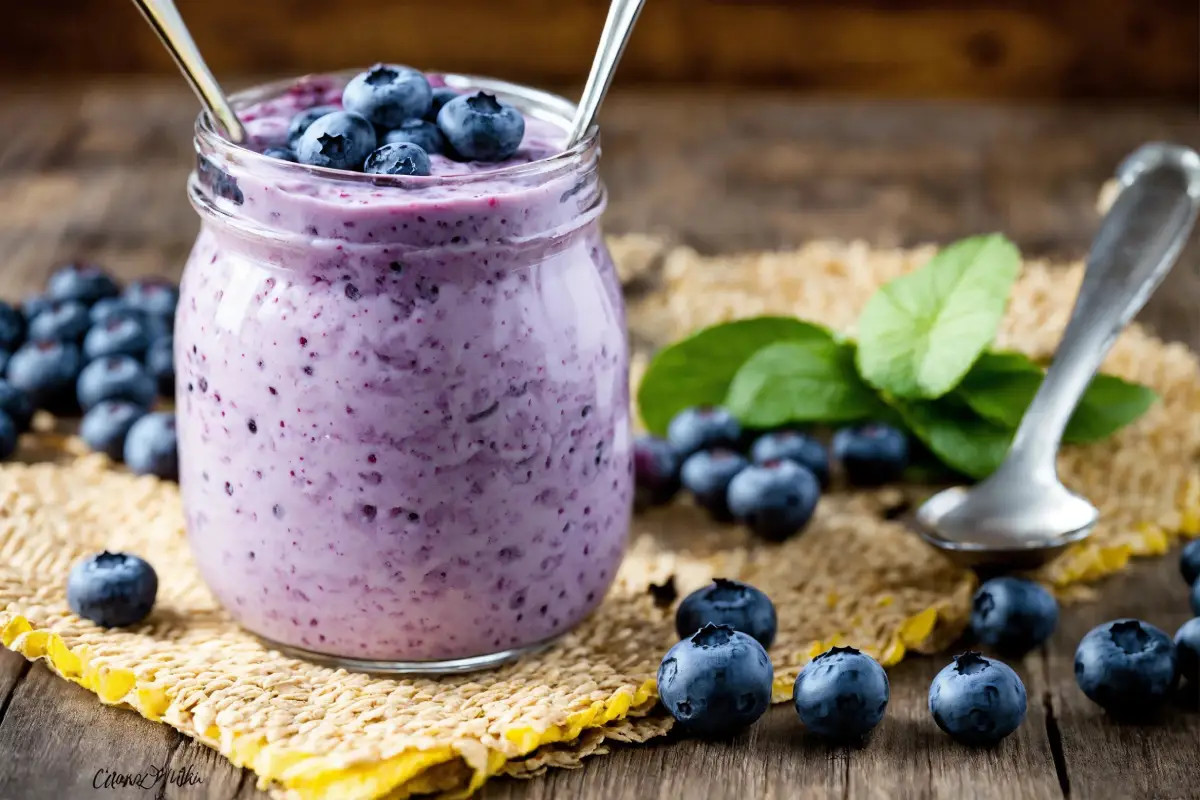 Creamy blueberry cream cheese in a jar, sprinkled with fresh blueberries and mint, ready to be served.