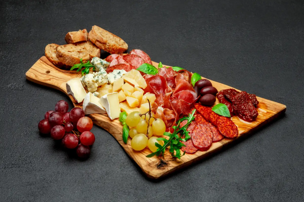An elegant charcuterie and cheese board with an assortment of meats, cheeses, and grapes.