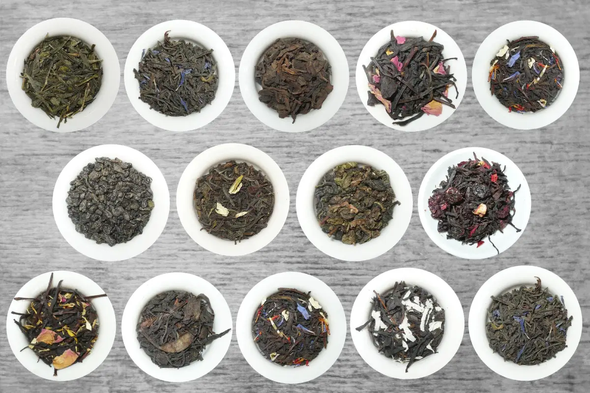 Various Earl Grey tea blends displayed in white bowls on a wooden surface.
