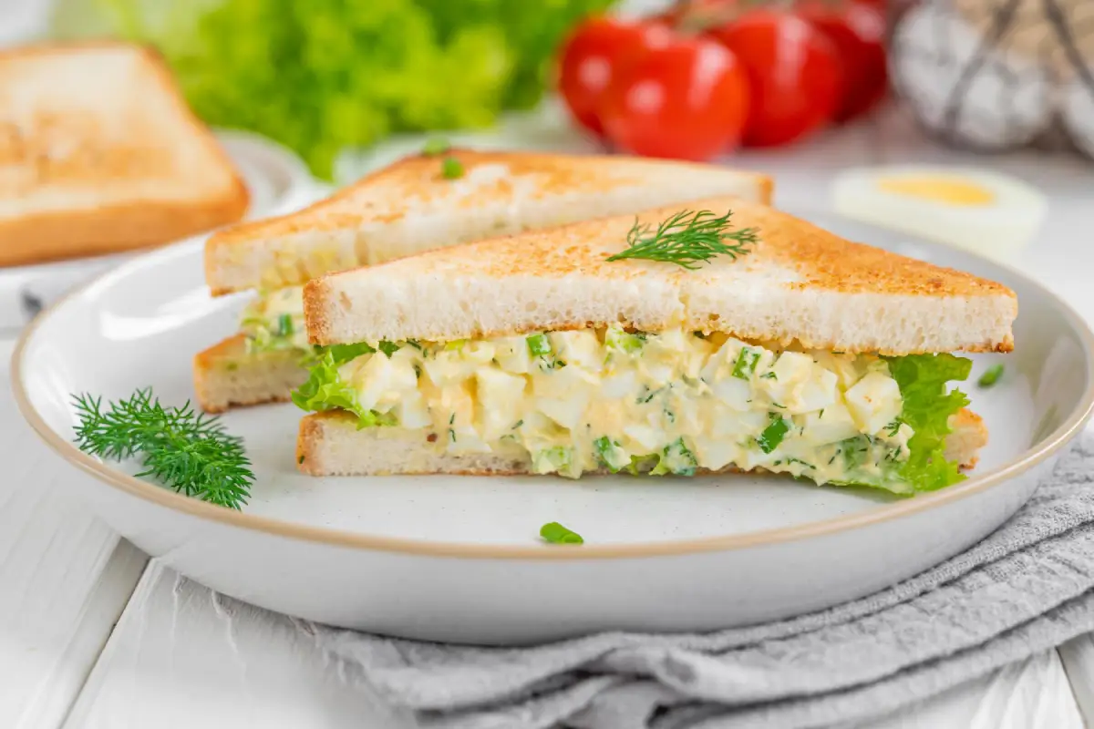 Egg salad sandwich on toasted bread with lettuce and dill, ready to be enjoyed.