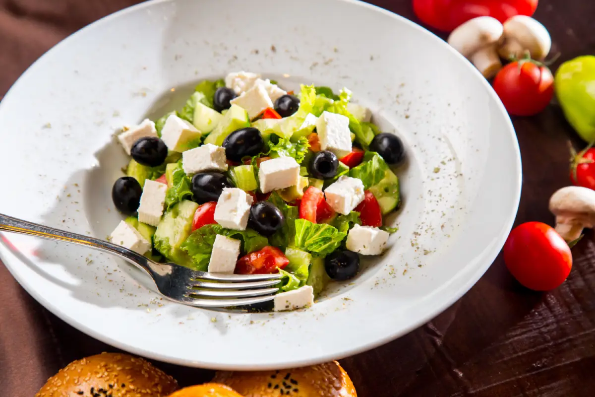 Greek salad with black olives, feta cheese, and fresh vegetables on a plate.