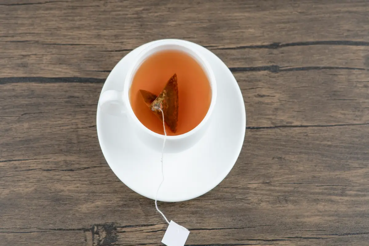Cup of Earl Grey tea with a tea bag on a wooden table.