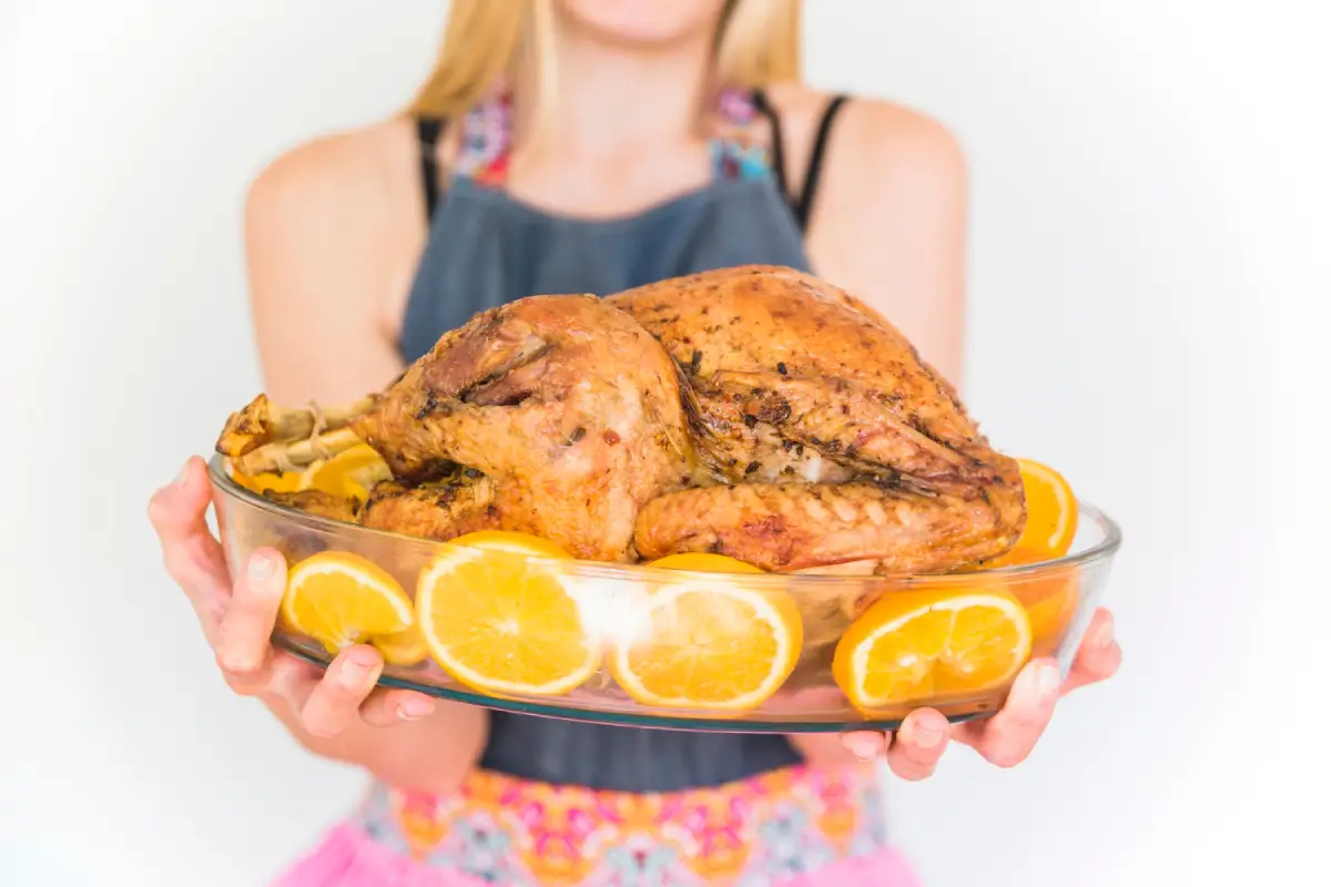 Woman presenting a beautifully basted turkey garnished with orange slices