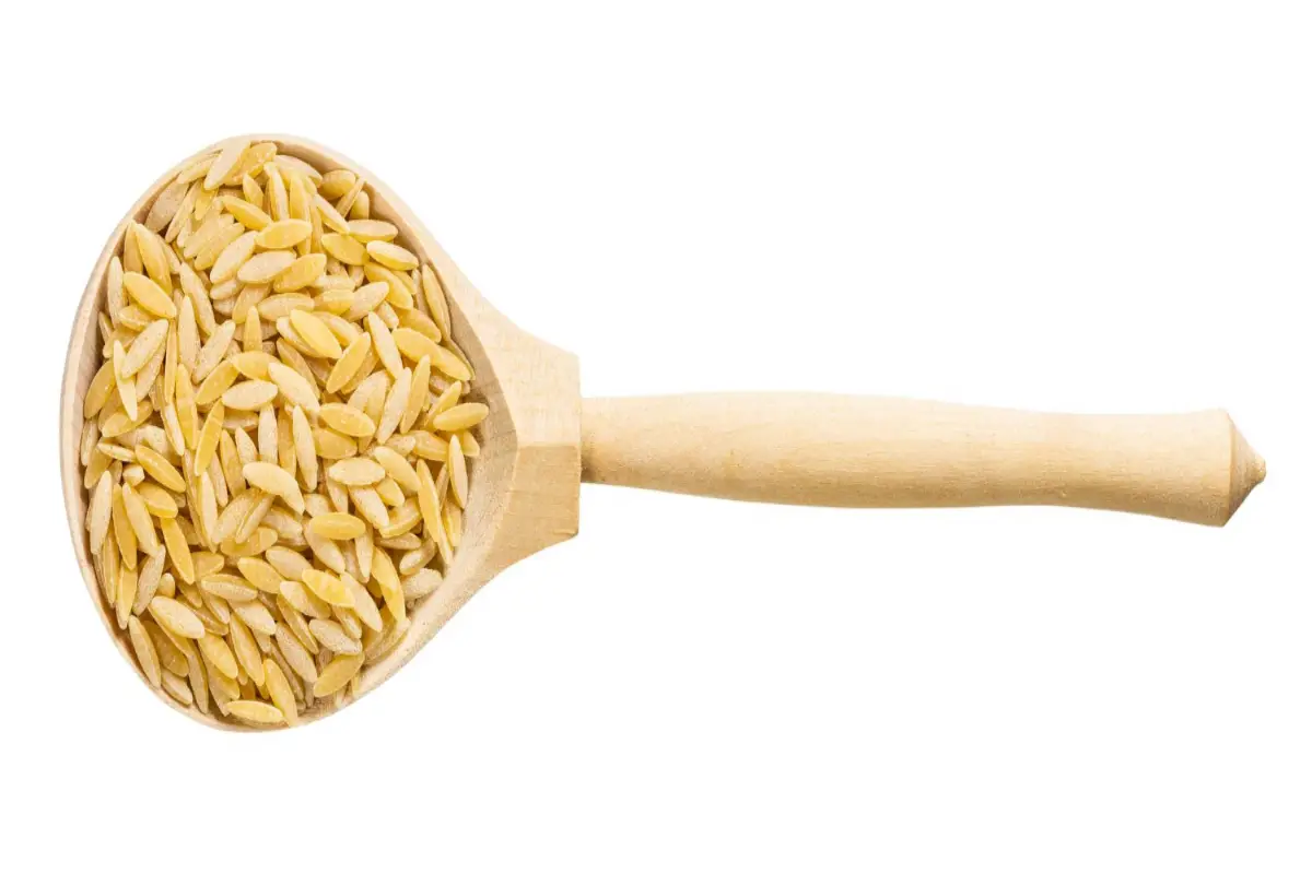 Top view of a wooden spoon filled with orzo pasta isolated on a white background.