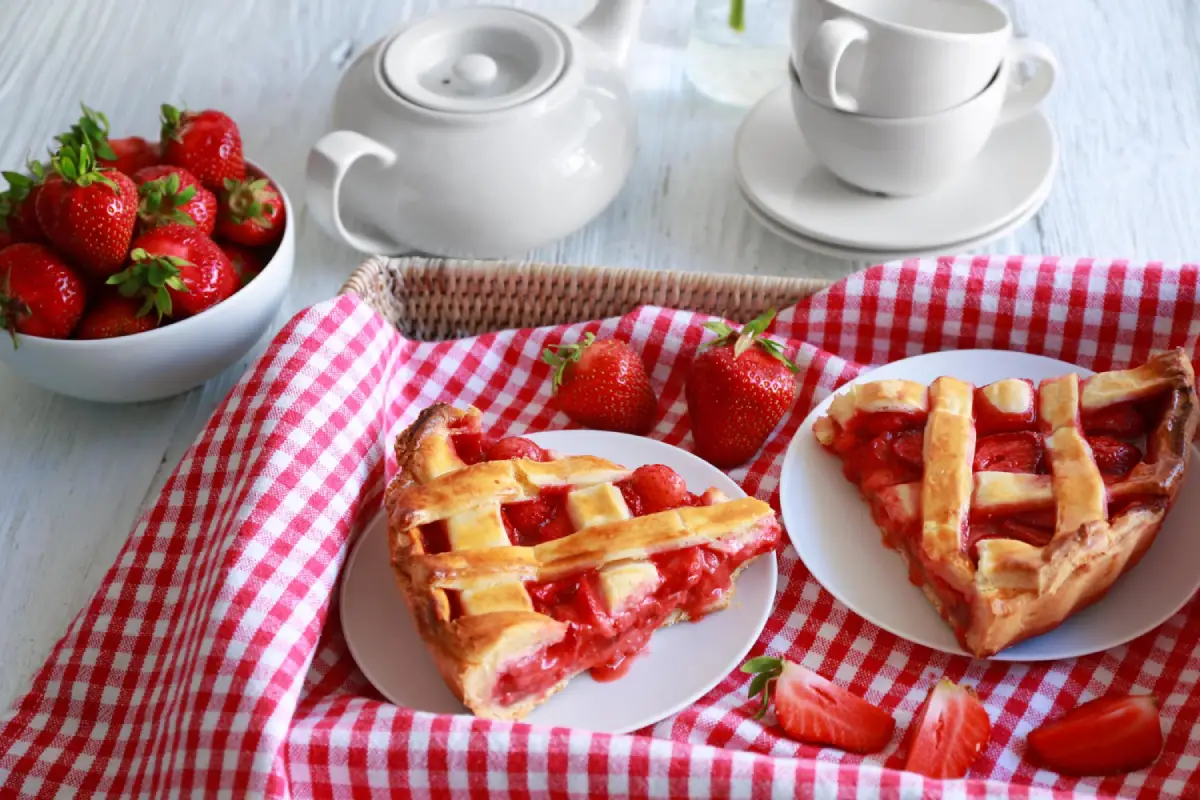 Freshly baked strawberry lattice pie on a table served with tea