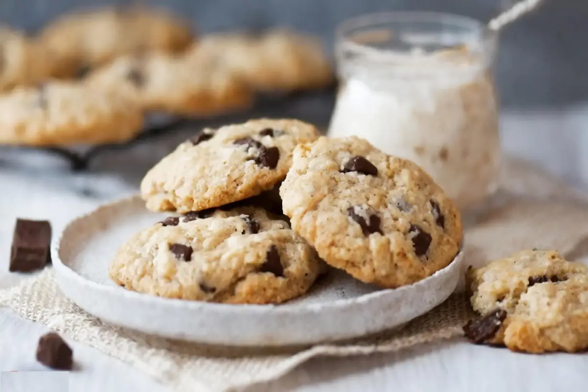 Cream cheese chocolate chip cookies with a glass of milk on a white tablecloth