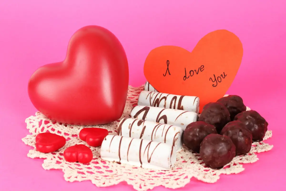 Valentine's Day confections with a heart-shaped note on a pink background