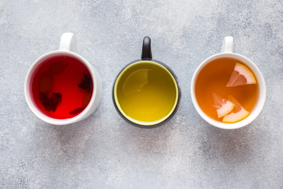 Three cups of different tea types showcasing variety in color and ingredients