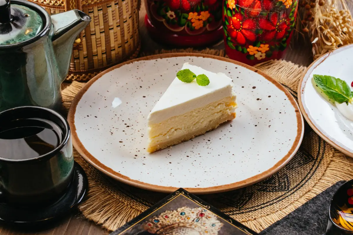 Artistic vanilla cheesecake slice on a speckled plate, with traditional decor.