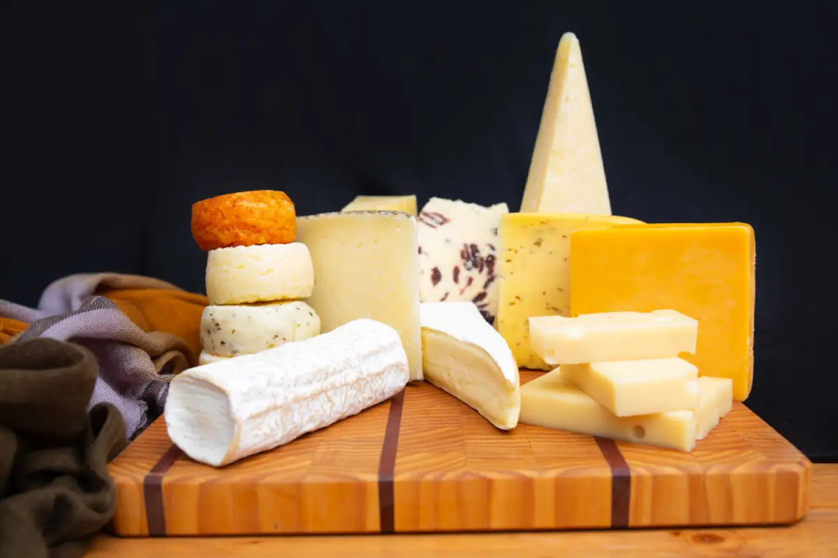 An assortment of cheeses displayed on a wooden cutting board.