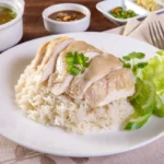 A plate of Authentic Malaysian Hainanese Chicken Rice with condiments.