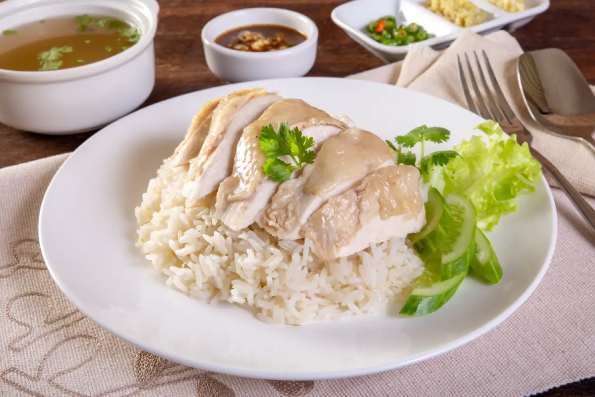 A plate of Authentic Malaysian Hainanese Chicken Rice with condiments.