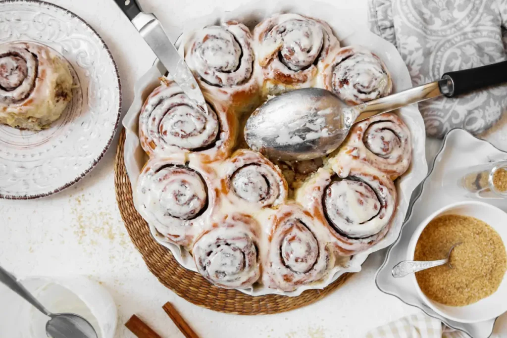 Freshly baked cinnamon rolls with creamy icing served on a table.