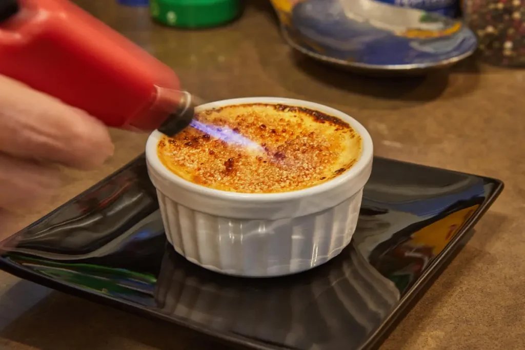 Caramelizing sugar on top of crab brulee with a kitchen torch