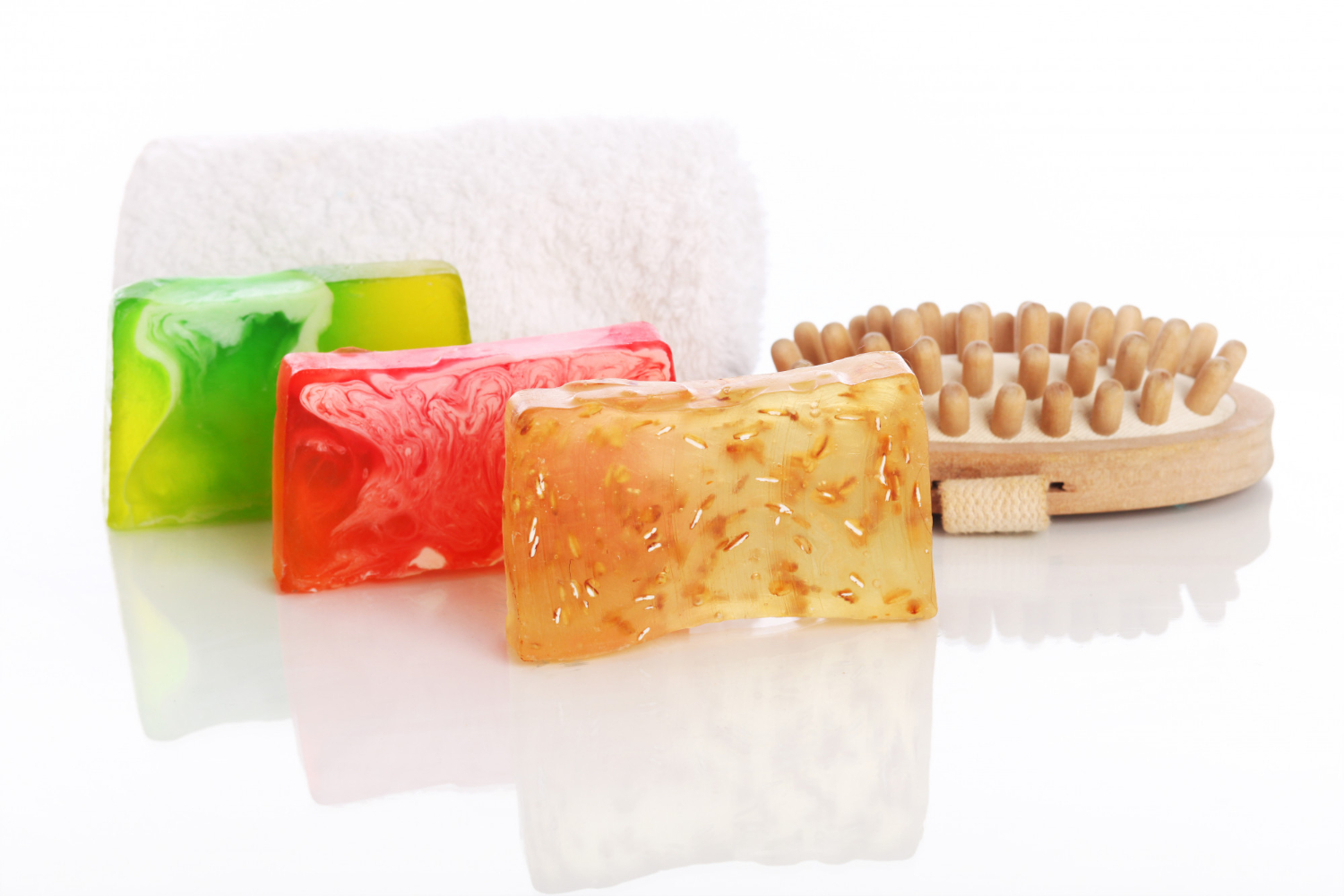 Brightly colored jelly soaps with a massage brush and fluffy white towel.