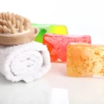 Colorful jelly soaps with a massaging brush on top of a rolled towel.